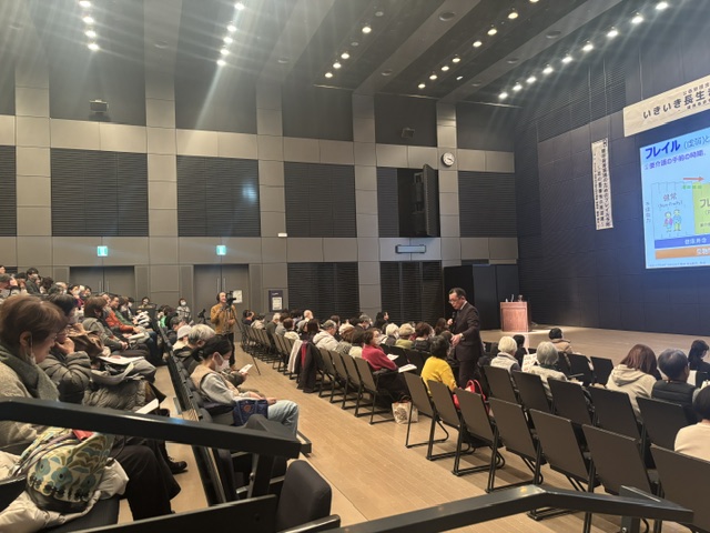 客席の近くで参加者と対話しながら講演する飯島勝矢先生