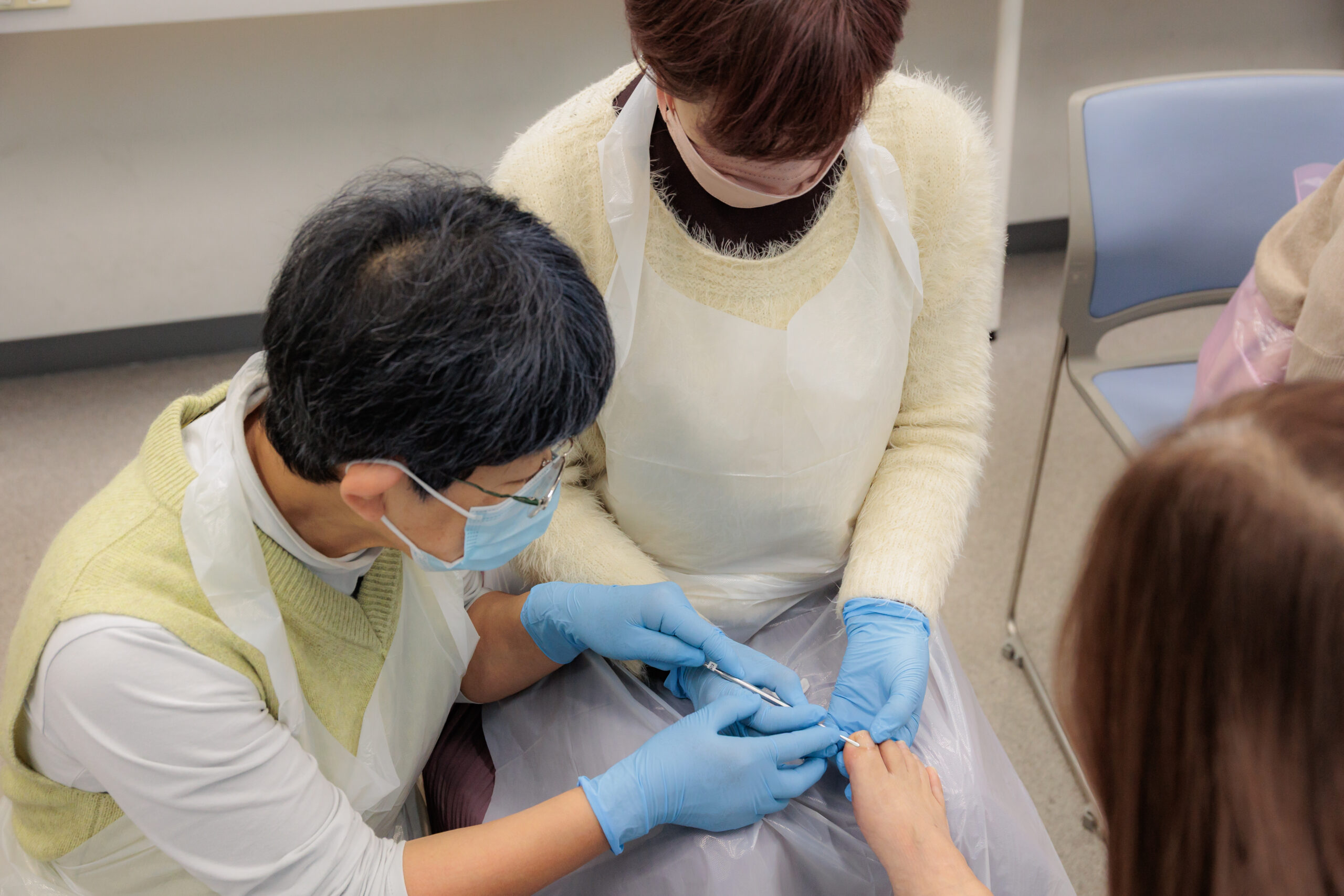 手元の動きを確認しながら足の爪のケアを学ぶ実技の様子